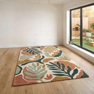 May include: A rectangular area rug with a cream background and a colorful leaf pattern. The leaves are in shades of green, orange, and yellow. The rug is placed on a light wood floor.