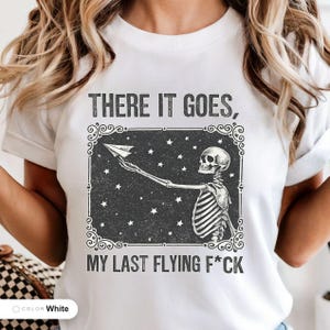 Model wearing a white t-shirt printed with "Last Nerve Bat-Free Skeleton" across the chest.