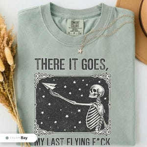 Bay t-shirt folded flat and photographed from above, printed with "Last Nerve Bat-Free Skeleton" across the chest.