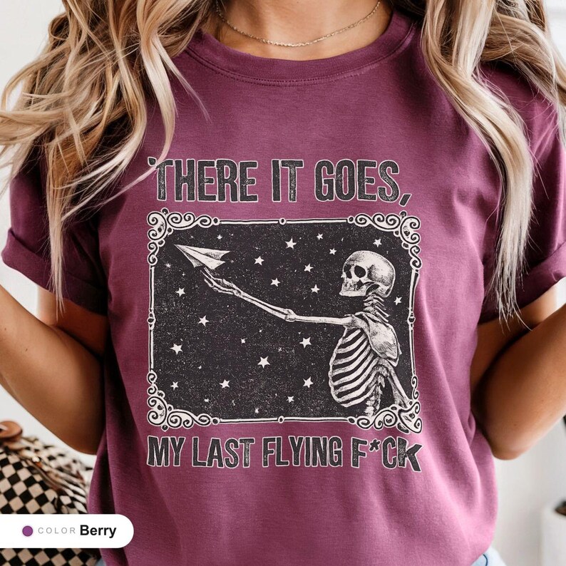 Model wearing a berry t-shirt printed with "Last Nerve Bat-Free Skeleton" across the chest.