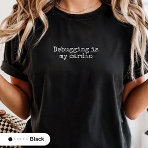 Model wearing a black t-shirt printed with "Debugging is my cardio" across the chest.