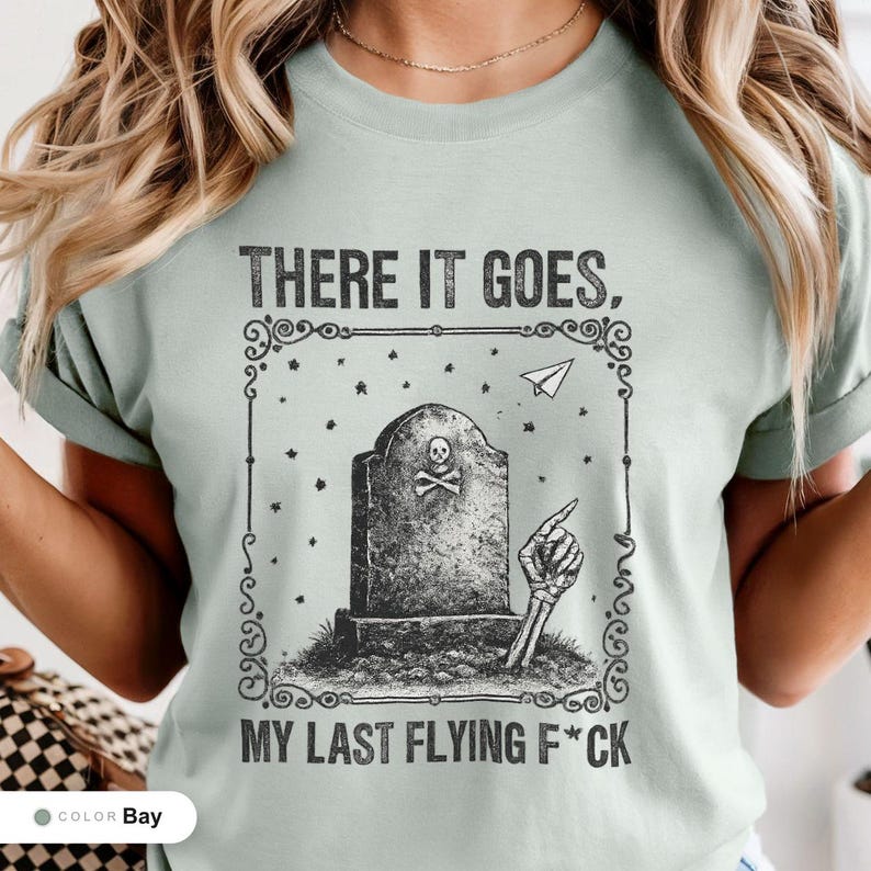 Model wearing a bay t-shirt printed with "Last Flying F*ck in the Graveyard" across the chest.