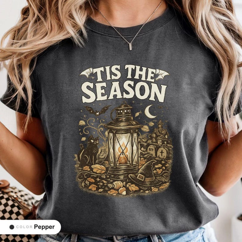 Model wearing a pepper shirt printed with "Haunted Harvest Lantern" across the chest.