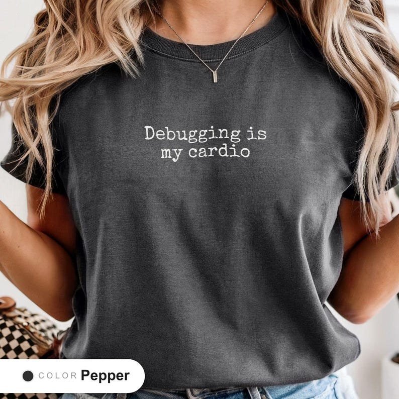 Model wearing a pepper t-shirt printed with "Debugging is my cardio" across the chest.