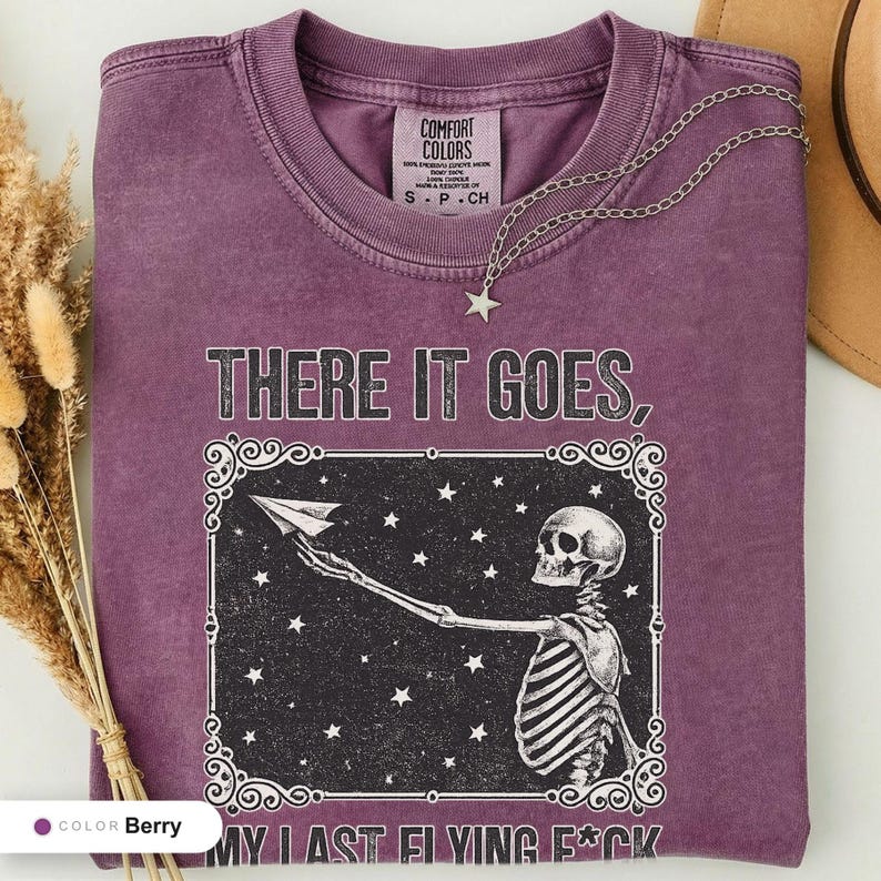 Berry t-shirt folded flat and photographed from above, printed with "Last Nerve Bat-Free Skeleton" across the chest.