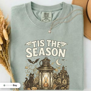 Bay shirt folded flat and photographed from above, printed with "Haunted Harvest Lantern" across the chest.