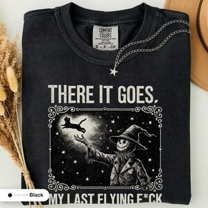Black t-shirt folded flat and photographed from above, printed with "Last Flight Skeleton Bat" across the chest.