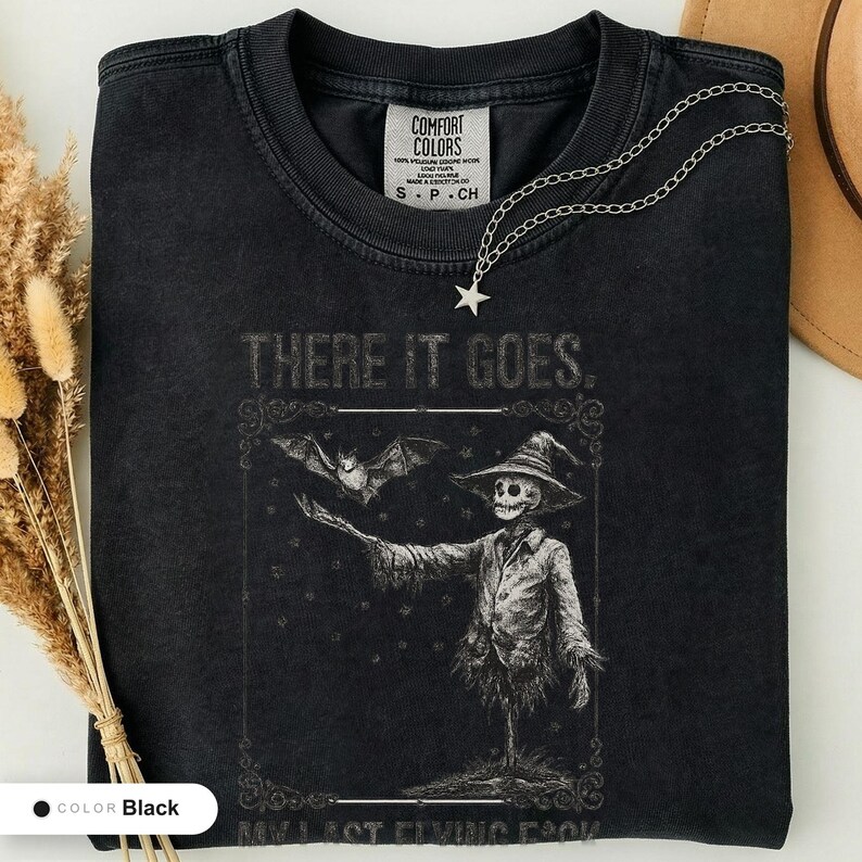 Black t-shirt folded flat and photographed from above, printed with "Graveyard Bat Catcher" across the chest.