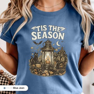 Model wearing a blue jean shirt printed with "Haunted Harvest Lantern" across the chest.