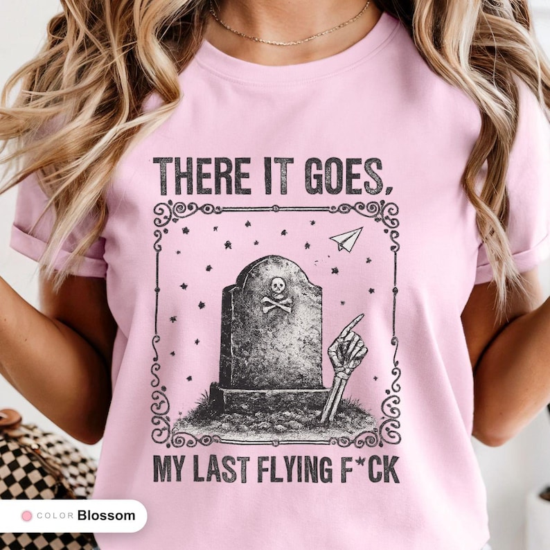 Model wearing a blossom t-shirt printed with "Last Flying F*ck in the Graveyard" across the chest.