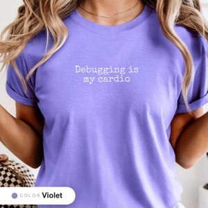 Model wearing a violet t-shirt printed with "Debugging is my cardio" across the chest.