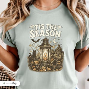 Model wearing a bay shirt printed with "Haunted Harvest Lantern" across the chest.
