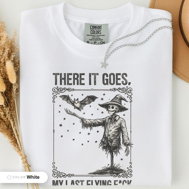White t-shirt folded flat and photographed from above, printed with "Graveyard Bat Catcher" across the chest.