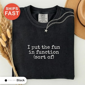 Op de afbeelding: Een zwart t-shirt met ronde hals en de wit geborduurde tekst I put the fun in function (sort of) op de borst. Het shirt heeft een Comfort Colors merklabel in de kraag en wordt gecombineerd met een zilveren ketting met sterhanger.