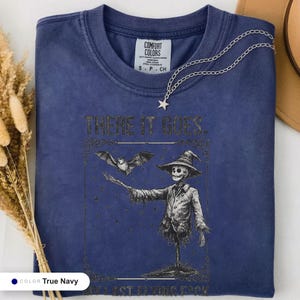 True navy t-shirt folded flat and photographed from above, printed with "Graveyard Bat Catcher" across the chest.