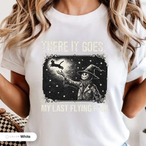 Model wearing a white t-shirt printed with "Last Flight Skeleton Bat" across the chest.