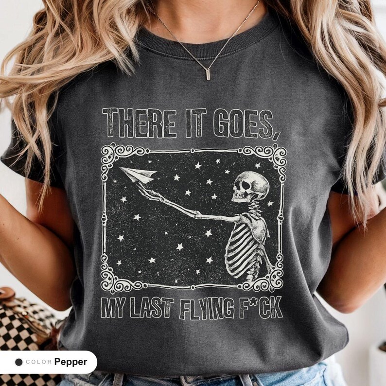 Model wearing a pepper t-shirt printed with "Last Nerve Bat-Free Skeleton" across the chest.