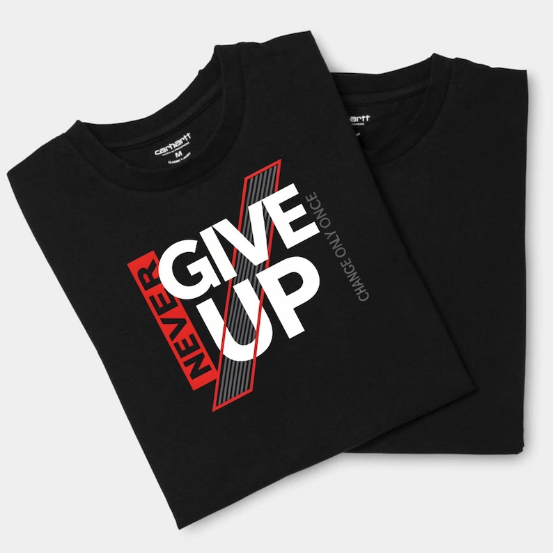 May include: Two black t-shirts with the text "NEVER GIVE UP" in white and red, with a gray striped design. The shirts also have the text "CHANCE ONLY ONCE" in gray. The Carhartt logo is visible on the collar.