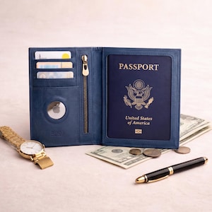 May include: A blue leather passport holder with a zip, card slots, and an AirTag. The passport holder is open, revealing a U.S. passport. A gold watch, pen, and cash are also visible.