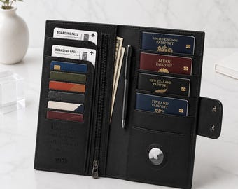 Könnte beinhalten: Eine schwarze Reisebrieftasche aus Leder mit mehreren Fächern für Kreditkarten, Bordkarten und vier Reisepässen aus dem Vereinigten Königreich, Japan, Neuseeland und Finnland. Sie enthält ein Reißverschlussfach, einen Stifthalter und ein AirTag-Fach.