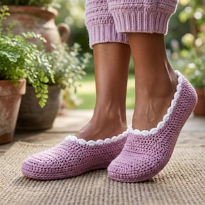 May include: A pair of lavender crochet slippers with a white scalloped trim. The slippers are worn with matching lavender knit pants. The image is taken outdoors, with potted plants in the background.