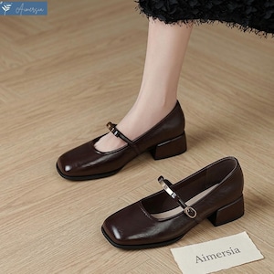 May include: Brown leather Mary Jane style shoes with a square toe and a small block heel. The shoes have a strap across the top with a gold-colored buckle. The brand name "Aimersia" is visible on a small tag.