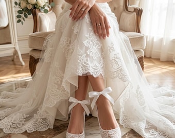 May include: White lace wedding shoes with pointed toes and ankle ribbons. The shoes are part of a bridal ensemble, with a white lace wedding dress and a bouquet of white roses in the background.