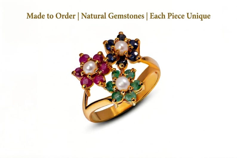Pu&ograve; includere: Un anello d'oro con tre motivi floreali, ciascuno con una perla centrale e pietre preziose. Un fiore ha rubini rossi, un altro zaffiri blu e il terzo smeraldi verdi. Il testo in alto recita: Made to Order | Natural Gemstones | Each Piece Unique.