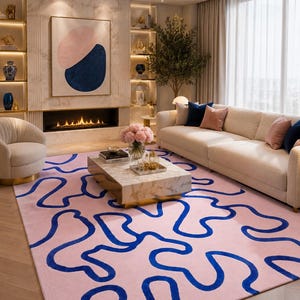 Può includere: Un tappeto rettangolare con uno sfondo rosa chiaro e un motivo continuo di linee ondulate astratte, spesse e blu scuro, che si snodano su tutta la superficie, creando un netto contrasto con il colore pastello di base del tessuto.