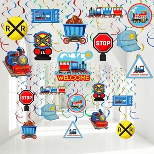 May include: A collection of train-themed decorations, including train cutouts, stop signs, railroad crossing signs, and train tickets. The decorations are in red, blue, and yellow, with the word "WELCOME" displayed prominently.
