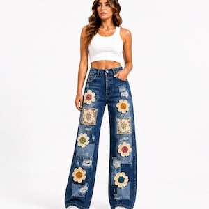 Könnte beinhalten: Hoch taillierte, weit geschnittene blaue Jeans aus Denim mit abgenutzten Stellen, ausgefransten Rissen und dekorativen Aufnähern. Die Applikationen umfassen verschiedene bunte gehäkelte Blumenmotive und rechteckige Stoffquadrate mit komplexen Blumenmustern.