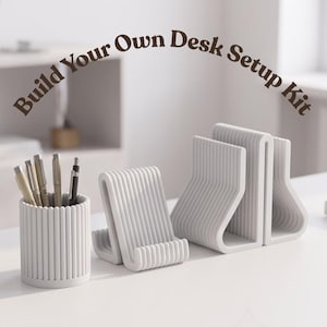 Può includere: Un set organizzatore da scrivania bianco composto da un portapenne cilindrico con dettagli a coste verticali, un piccolo supporto per telefono e un supporto per documenti più grande, tutti con texture a coste. Il testo Build Your Own Desk Setup Kit è visibile.