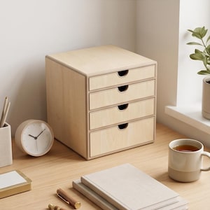 Peut inclure: Un organisateur de bureau en bois clair doté de quatre tiroirs superposés avec des découpes semi-circulaires en guise de poignées. L'unité présente une finition lisse en grain de bois naturel et un cadre carré pour le rangement.