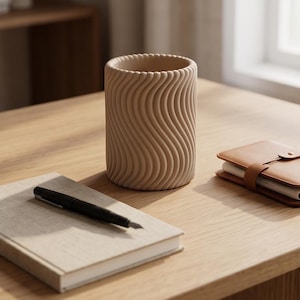 Peut inclure: Un porte-stylo cylindrique de couleur beige présentant une texture verticale ondulée et nervurée sur toute sa surface extérieure. Le récipient possède une ouverture circulaire sur le dessus et est disposé verticalement.