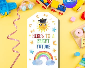 Puede incluir: Una etiqueta de regalo blanca con una ilustración de acuarela de un sol con un gorro de graduación y gafas de sol. El texto "HERE'S TO A BRIGHT FUTURE" está escrito en letras de colores debajo del sol. Un arcoíris con nubes está debajo del texto.