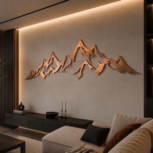 Könnte beinhalten: Ein großes, horizontales Wandkunstobjekt aus Metall, das ein stilisiertes Gebirge mit gezackten, unebenen Gipfeln darstellt. Die Skulptur hat ein warmes, kupferfarbenes Metallic-Finish mit strukturierter Oberfläche und ist an der Wand montiert.