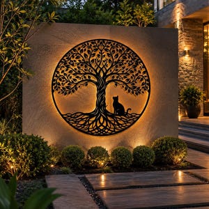May include: A circular black metal wall art piece featuring a detailed tree of life design with a silhouette of a cat sitting at the base. The artwork is mounted on a stone wall and is backlit with a warm glow that illuminates the intricate branches.