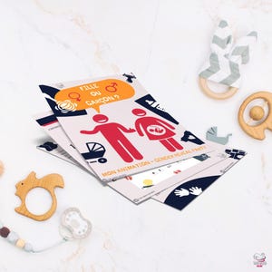 Puede incluir: Tarjetas de anuncio de fiesta de revelación de género con gráficos rojos y negros. Las tarjetas presentan el texto "Fille ou Garçon?" y "Mon Animation - Gender Reveal Party". Juguetes de madera para bebés y un chupete están dispersos.