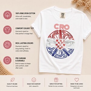 May include: A white short-sleeve t-shirt featuring a circular graphic with the text CRO above it. The graphic contains a red, white, and blue design with a checkered pattern in the center. The shirt has a Comfort Colors label at the neck.