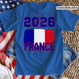 May include: Royal blue t-shirt with the text "2026" in blue and red. Below the text is a stylized French flag with the word "FRANCE" in red. The shirt is made of Gildan 5000B material.