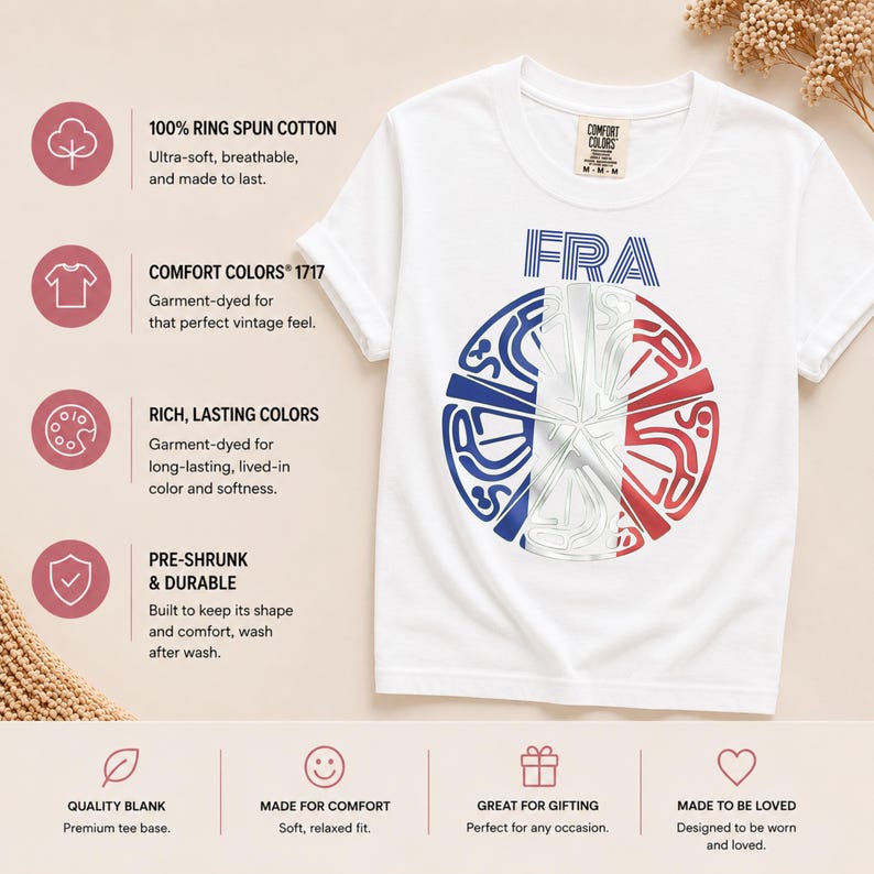 May include: A white short-sleeve t-shirt featuring a circular graphic with the text FRA above it. The graphic contains a stylized design in blue, white, and red. The shirt has a Comfort Colors label at the neck and is made of 100% ring spun cotton.