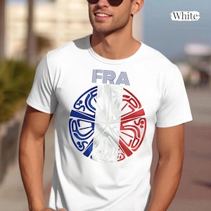 May include: A white short-sleeved t-shirt featuring a circular graphic on the chest. The graphic displays the text FRA above a stylized circular design colored in blue, white, and red, incorporating abstract line art patterns throughout the circle.