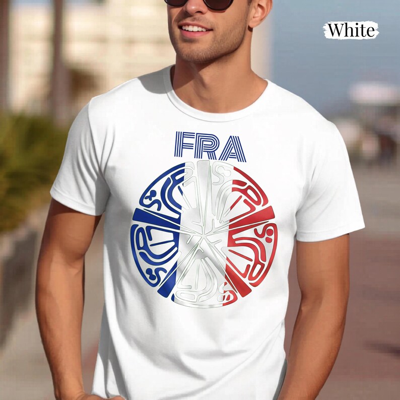 May include: A white short-sleeved t-shirt featuring a circular graphic on the chest. The graphic displays the text FRA above a stylized circular design colored in blue, white, and red, incorporating abstract line art patterns throughout the circle.