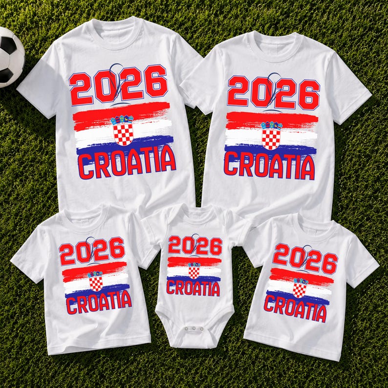 May include: White t-shirts and a onesie with a Croatian flag design. The shirts display the year "2026" in red, along with the word "CROATIA". The design includes red, white, and blue brushstrokes, and a checkered emblem.