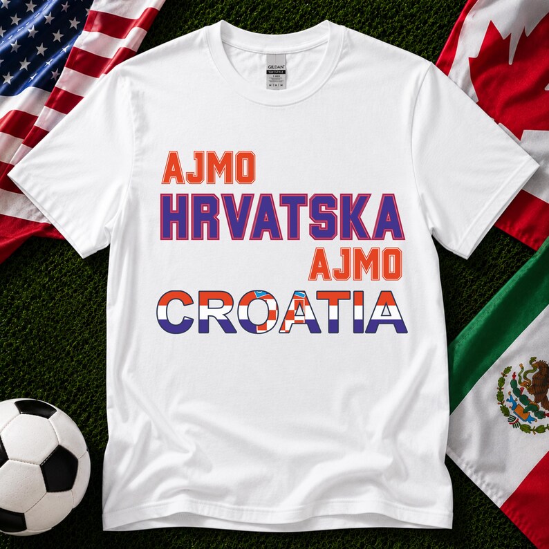 May include: A white short-sleeved t-shirt featuring the orange text AJMO, the purple text HRVATSKA, the orange text AJMO, and the word CROATIA in blue, with the letters filled with a red, white, and blue checkered pattern.