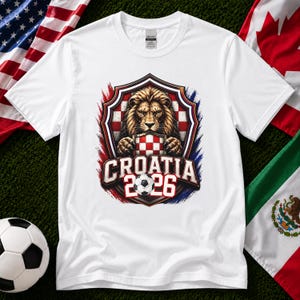 May include: White t-shirt featuring a lion graphic holding a Croatian checkered emblem. The design includes the text "CROATIA 2026" and a soccer ball. The shirt is surrounded by red, white, and blue accents.