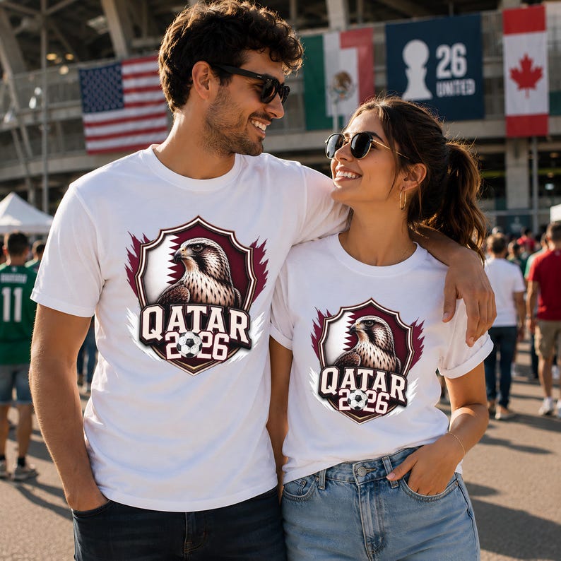 May include: White t-shirts featuring a shield design with a falcon, the text "QATAR 2026", and a soccer ball. The shirts are worn by a couple, with flags in the background.