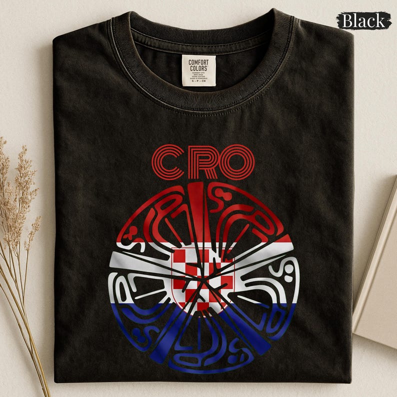 May include: A black short-sleeved t-shirt featuring the text CRO above a circular graphic. The graphic contains a red and white checkered pattern in the center, surrounded by stylized red, white, and blue lines forming a circular design.