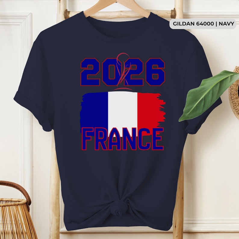 May include: Navy blue t-shirt with the text "2026 FRANCE" in red and blue, featuring the French flag. The shirt is a Gildan 64000 in navy.