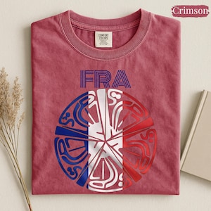May include: A crimson short-sleeve t-shirt featuring the text FRA in blue and a circular graphic design below it. The graphic is divided into segments colored in blue, white, and red, resembling the French flag with intricate line patterns.